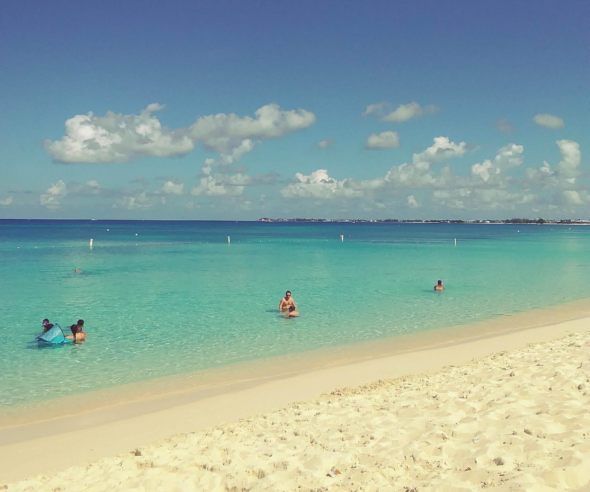 People swimming in the ocean on a sunny day.